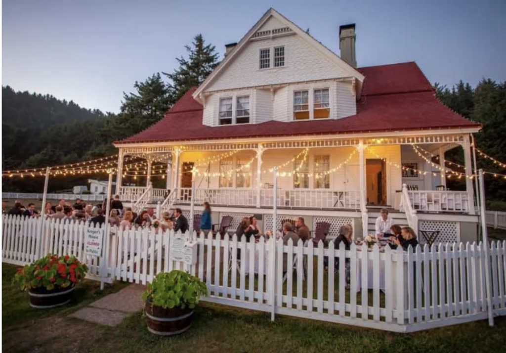 Guests enjoy an al fresco reception under string lights at Heceta Lighthouse, a charming and historic coastal wedding location.